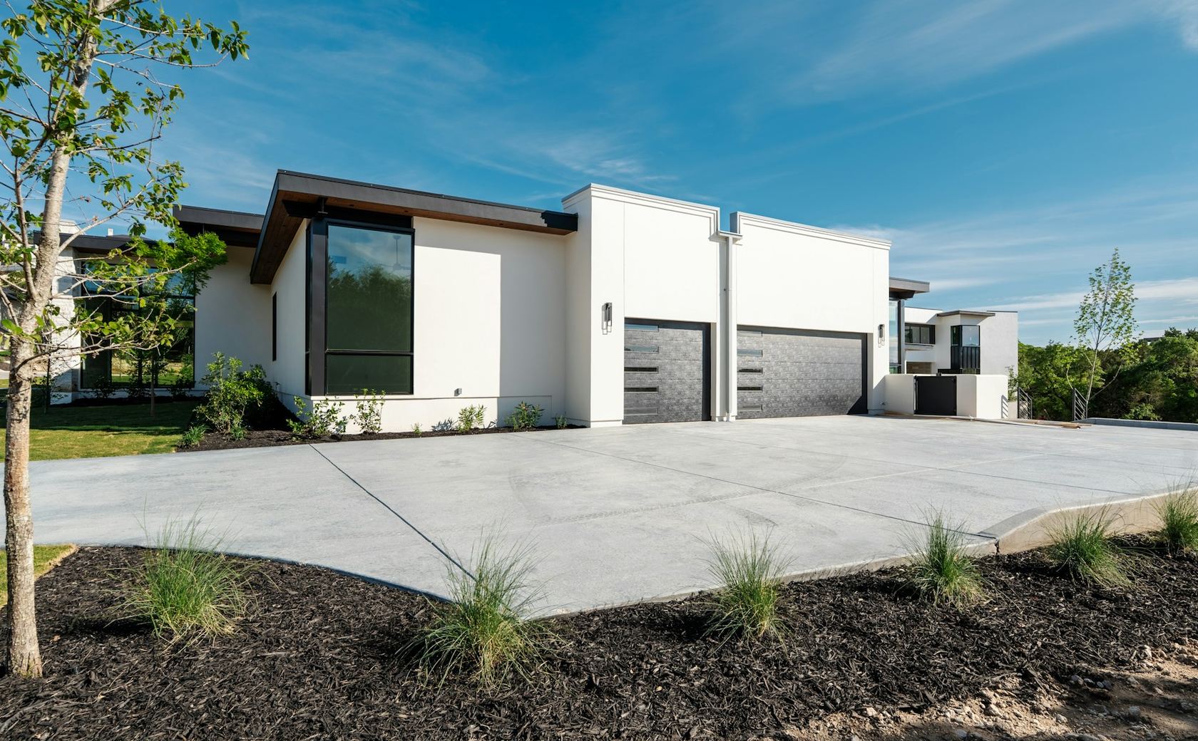 A modern home with a wide, freshly finished concrete driveway