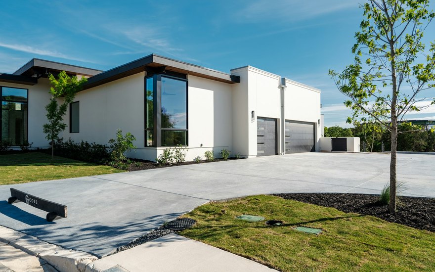 A wide, freshly finished light-grey concrete driveway and walkway at a modern home