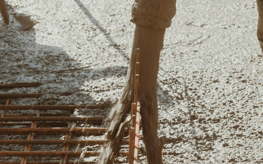 Fresh wet concrete being spread and screeded over a prepared driveway base