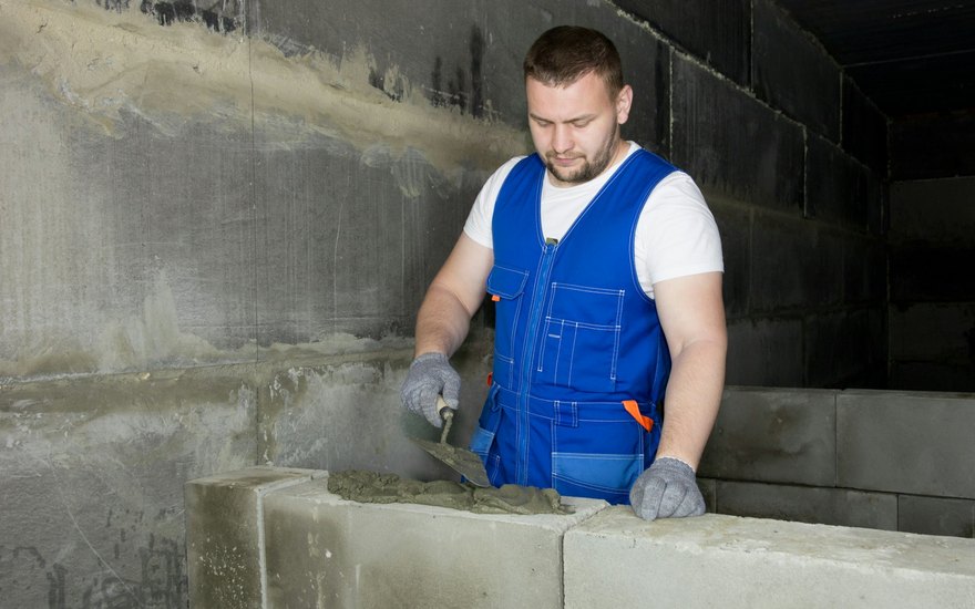 A concrete worker hand-finishing and smoothing a cement surface with a trowel