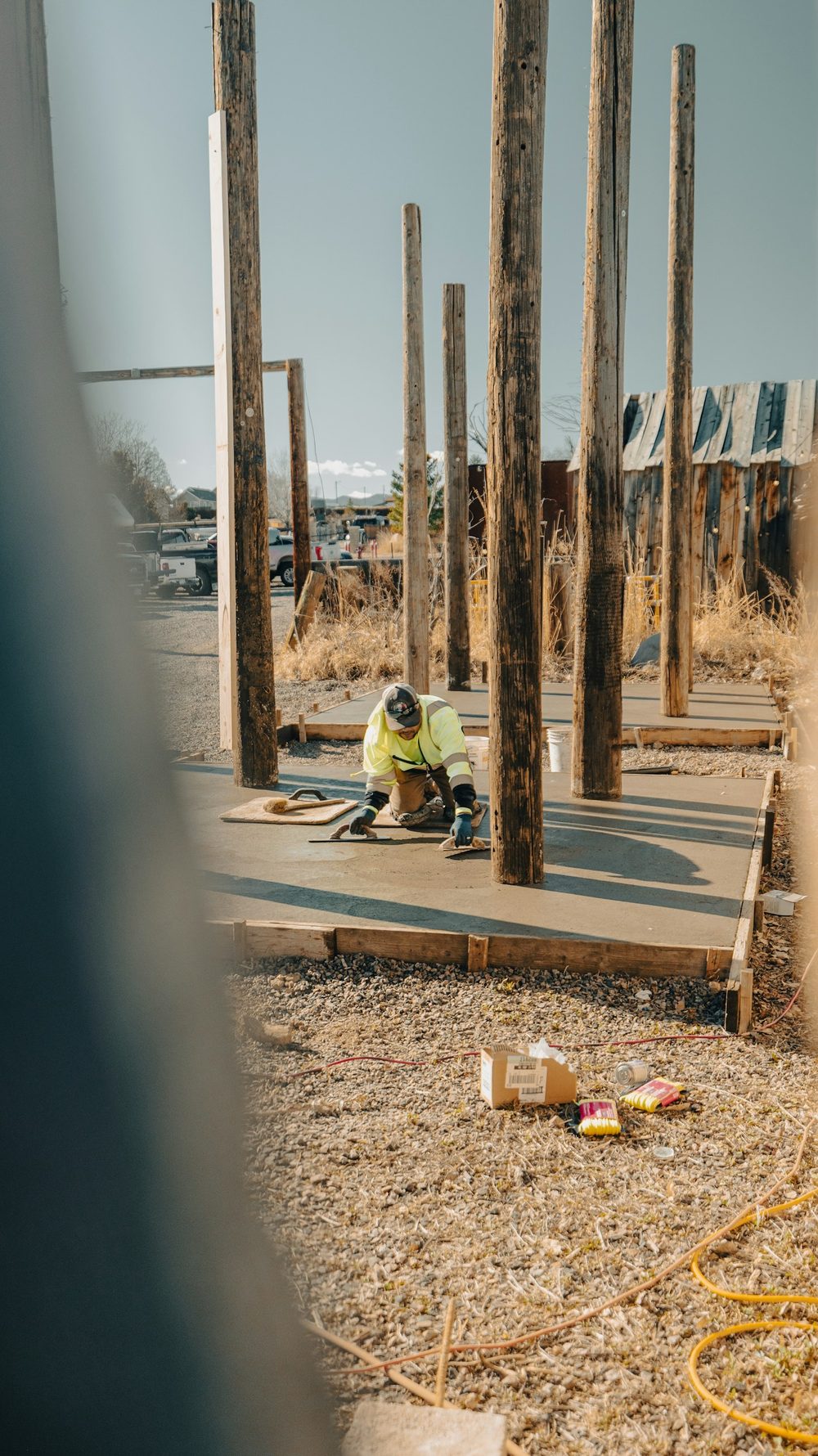 Concrete finisher kneeling on a formed slab, hand-troweling the fresh surface smooth