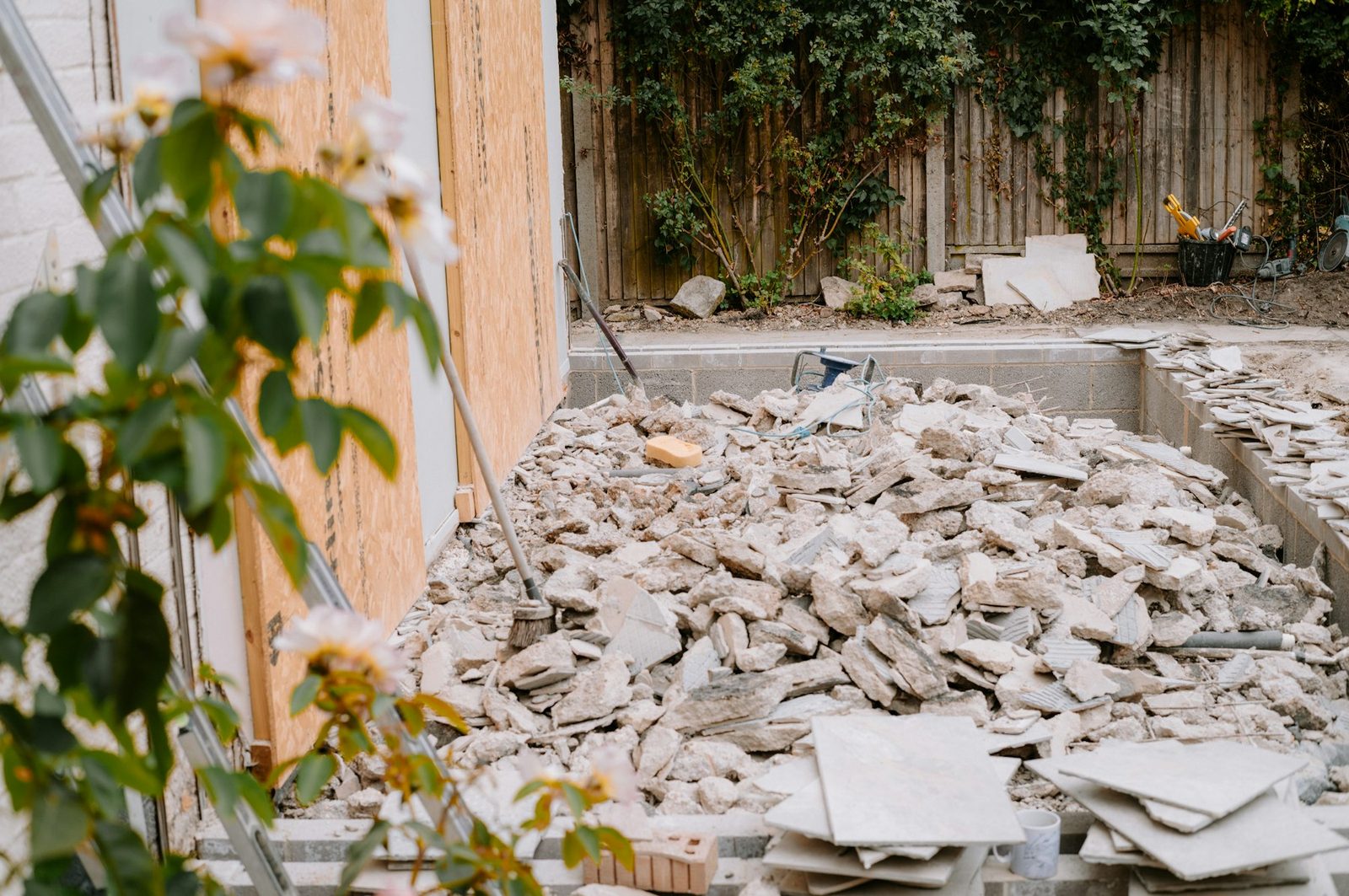Broken-up concrete slab piled beside a house after tear-out, ready to be hauled away