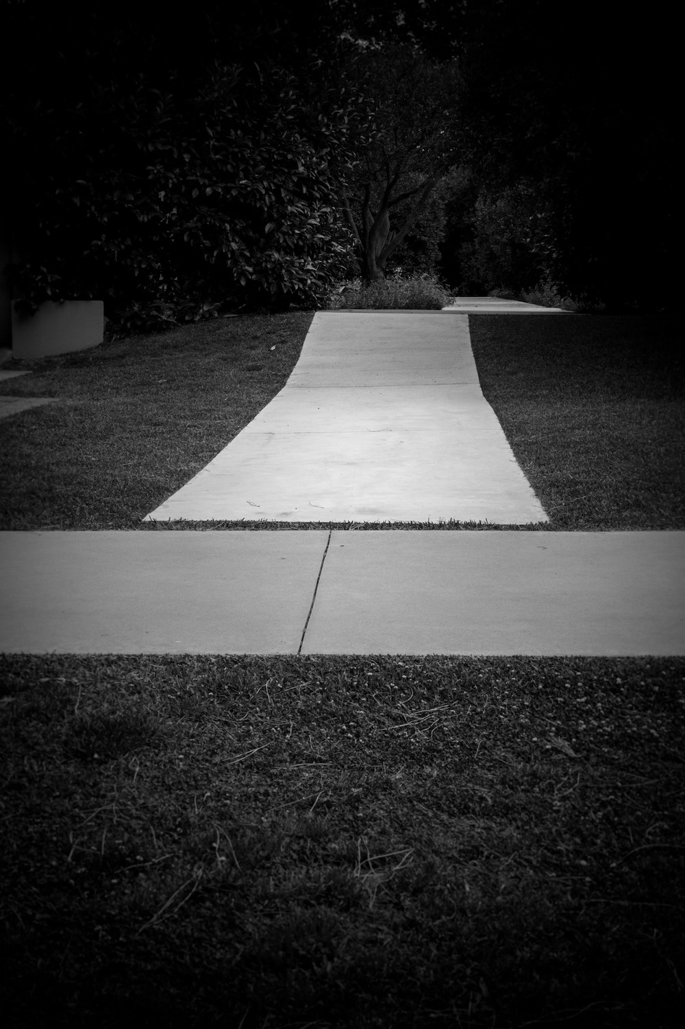 Finished concrete walkway running across a lawn to meet the public sidewalk