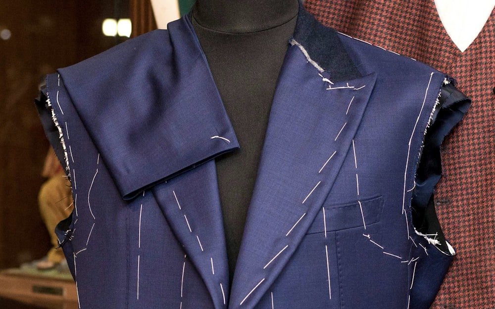A formal suit jacket being hand-tailored on a dress form