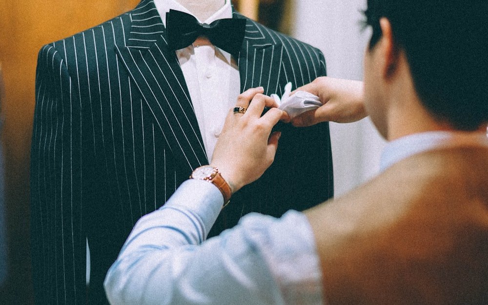 Tailor fitting and adjusting a suit jacket on a client