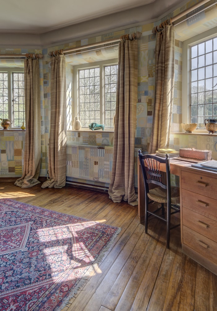 Warm honey-toned wood plank floor running through a sunlit room with a patterned rug
