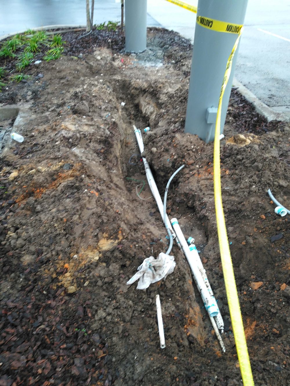 Irrigation lines dug out and repaired along a commercial landscape bed