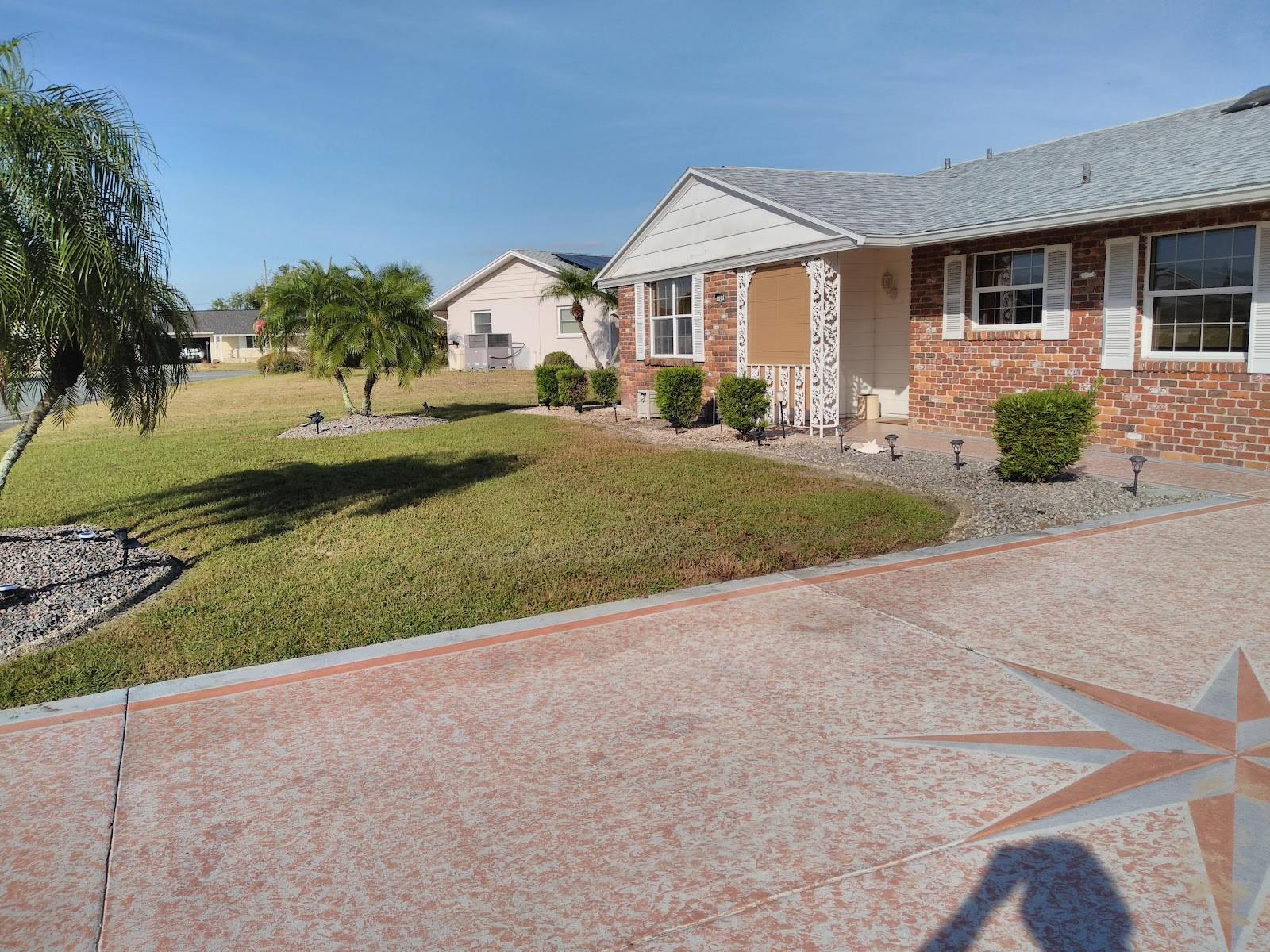 A healthy, freshly watered green front lawn with palms and a bright blue Florida sky