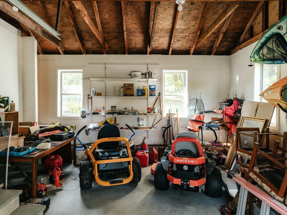 A cluttered garage full of tools, furniture and boxes ready for a cleanout