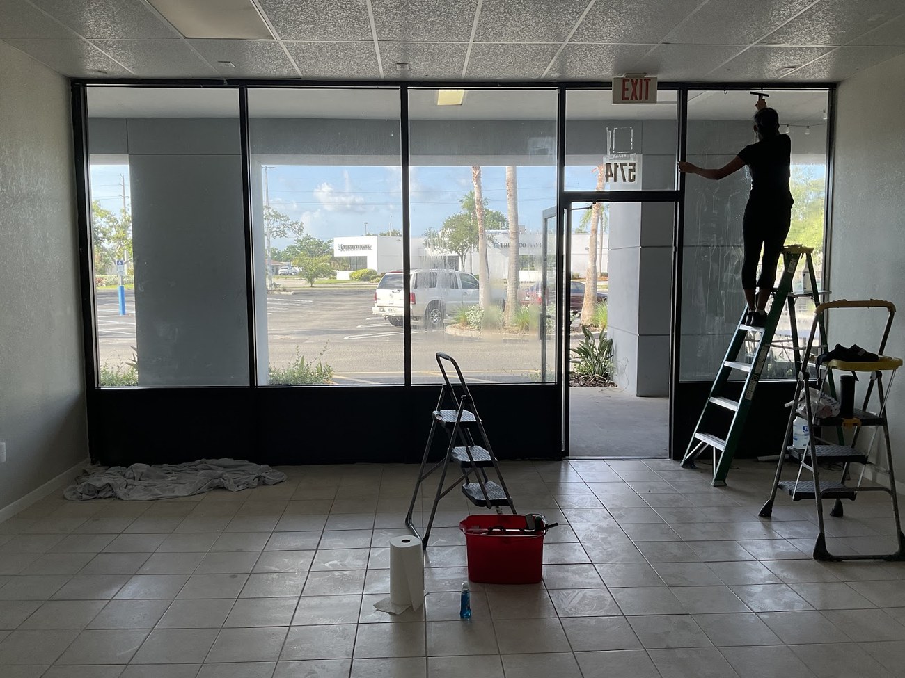 Installer on a ladder applying window film to a large commercial storefront window